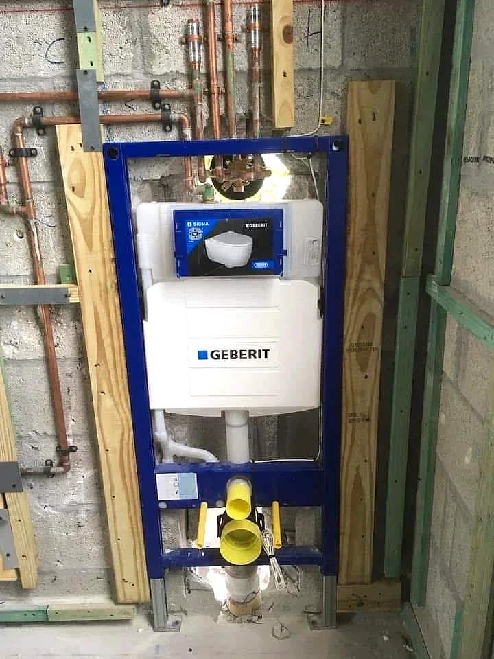 In-wall toilet carrier roughed in during a build-out