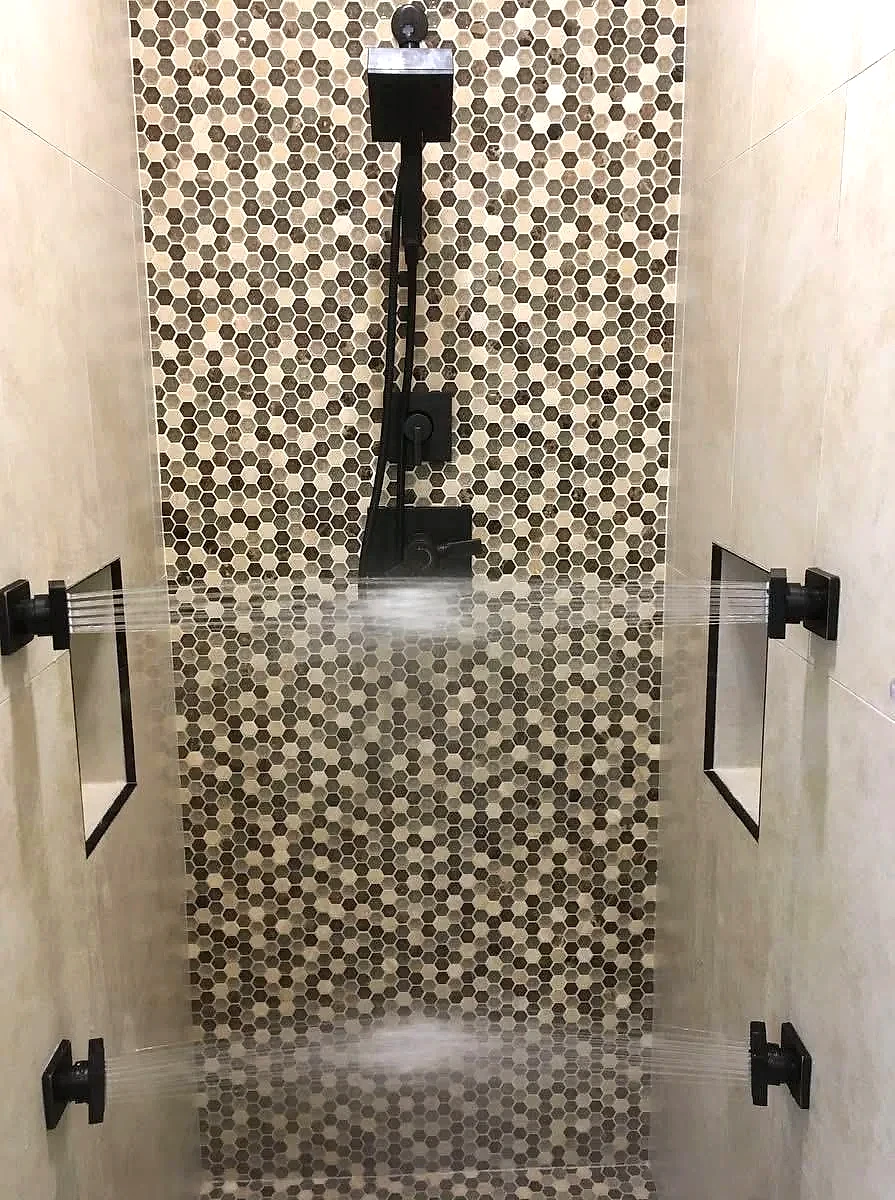 Matte black rain shower installed over pebble tile, Florida bathroom